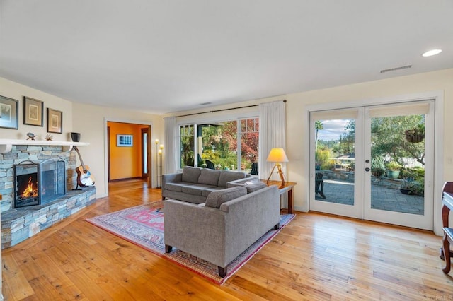 living room featuring french doors, a fireplace, and light hardwood / wood-style flooring