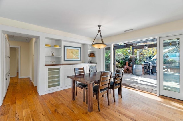 dining space featuring built in shelves, beverage cooler, and light wood-type flooring