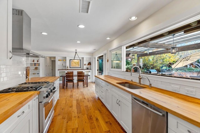 kitchen with pendant lighting, appliances with stainless steel finishes, butcher block counters, and white cabinets