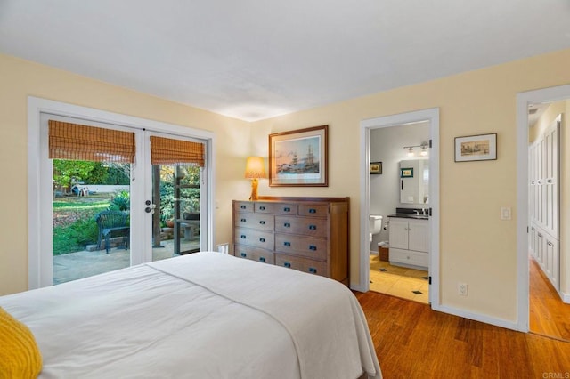 bedroom with connected bathroom, access to outside, light hardwood / wood-style floors, and french doors