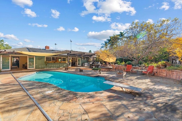 view of swimming pool with a patio and a diving board