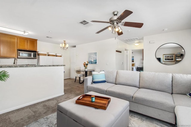 living room with ceiling fan with notable chandelier and light carpet