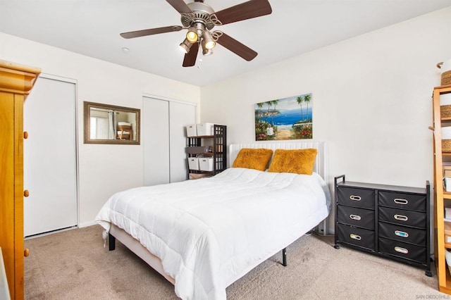 bedroom featuring multiple closets, light colored carpet, and ceiling fan