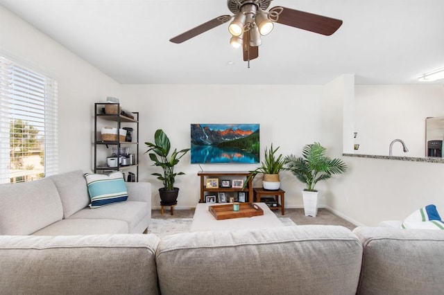 living room with light carpet, sink, and ceiling fan