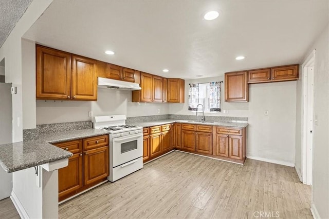 kitchen with white gas range, light hardwood / wood-style flooring, a kitchen breakfast bar, and sink