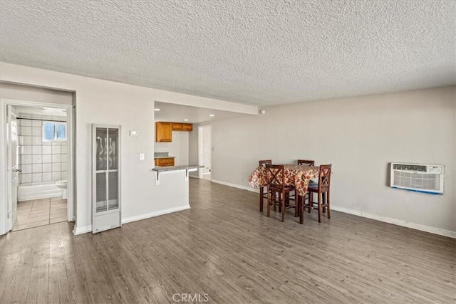 dining space with an AC wall unit, a textured ceiling, and dark hardwood / wood-style flooring