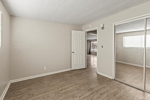 unfurnished bedroom featuring hardwood / wood-style floors, a closet, and a textured ceiling