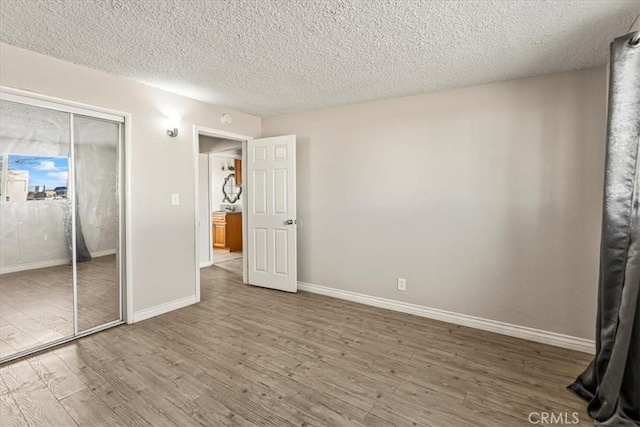 unfurnished bedroom featuring wood-type flooring, a textured ceiling, and a closet