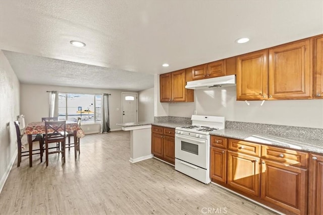 kitchen featuring white gas range, a textured ceiling, and light wood-type flooring