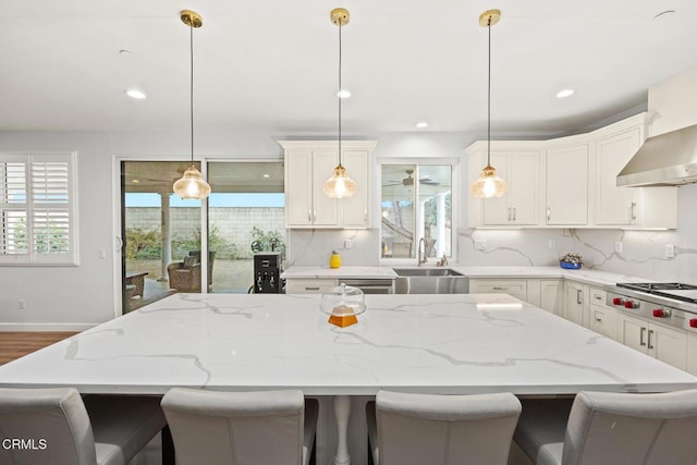 kitchen with stainless steel gas stovetop, decorative light fixtures, a center island, and sink