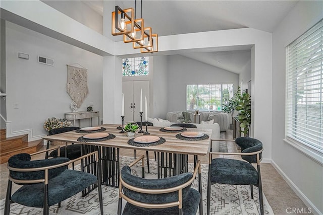 dining room featuring light tile patterned floors, plenty of natural light, vaulted ceiling, and a notable chandelier