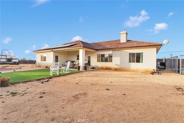 back of property featuring a lawn and solar panels