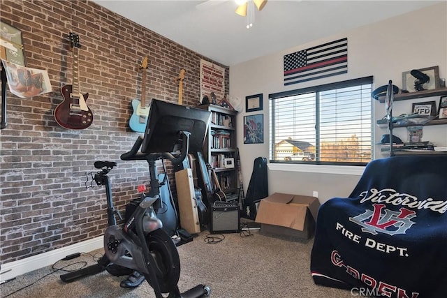 workout area with ceiling fan and brick wall