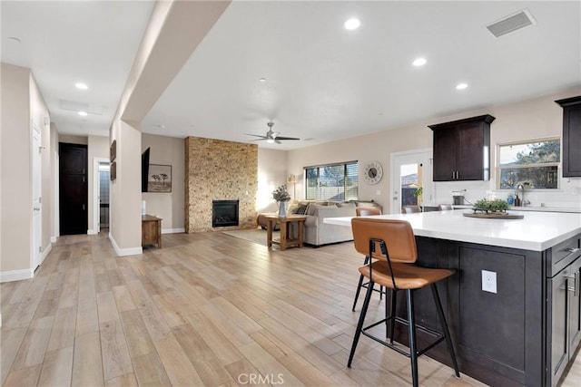 kitchen with a fireplace, light hardwood / wood-style floors, plenty of natural light, and a kitchen island