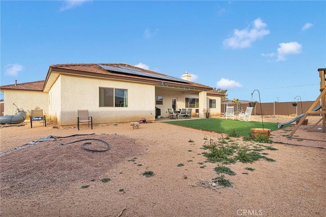 back of property with a patio and solar panels