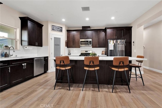 kitchen with a kitchen island, appliances with stainless steel finishes, sink, and a kitchen breakfast bar