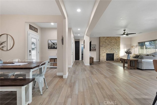 interior space featuring ceiling fan, a large fireplace, and light wood-type flooring