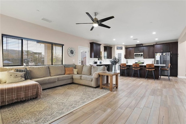 living room featuring ceiling fan and light hardwood / wood-style flooring