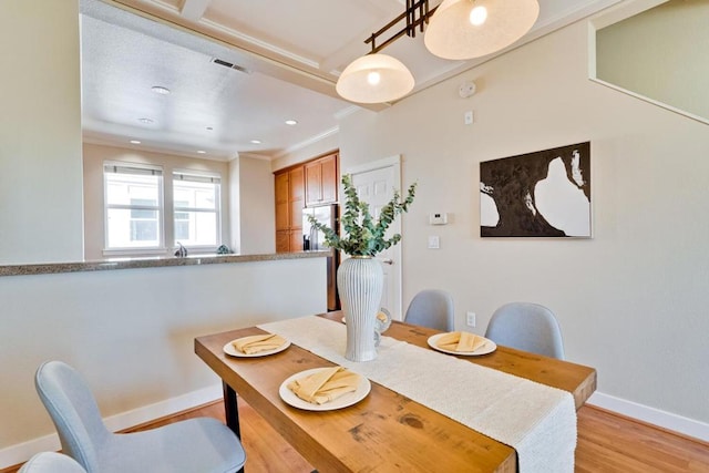 dining room with ornamental molding and light wood-type flooring