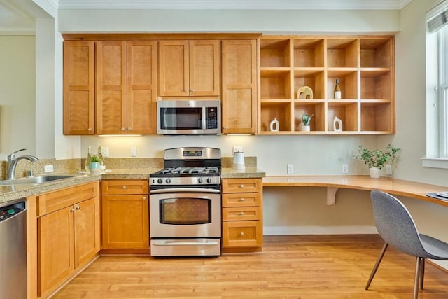 kitchen with sink, crown molding, built in desk, light hardwood / wood-style flooring, and appliances with stainless steel finishes