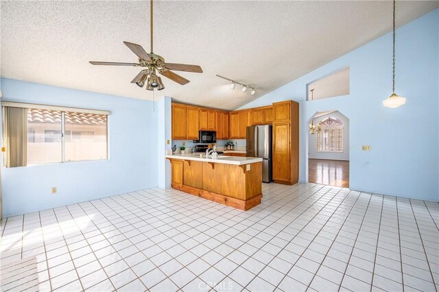 kitchen featuring a breakfast bar, decorative light fixtures, a textured ceiling, stainless steel fridge, and kitchen peninsula