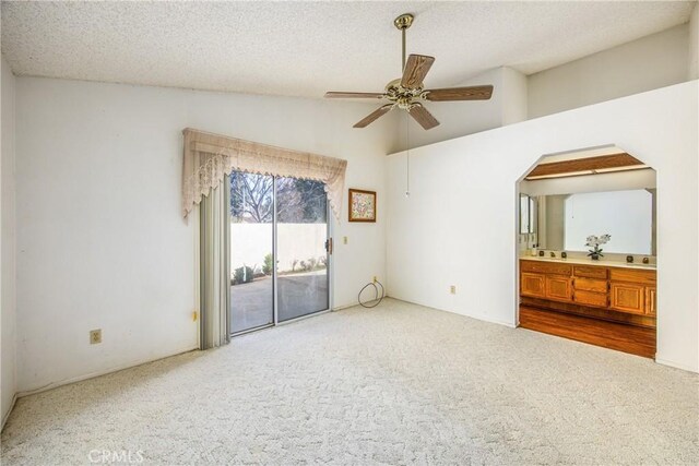 carpeted empty room with lofted ceiling, ceiling fan, and a textured ceiling