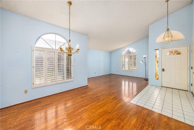 entryway featuring vaulted ceiling, hardwood / wood-style floors, a wealth of natural light, and a notable chandelier