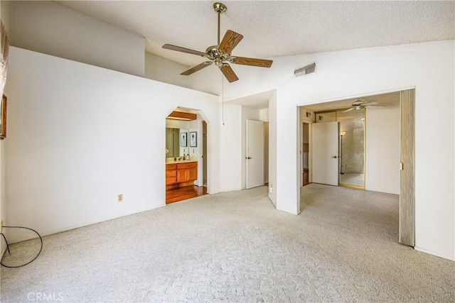 interior space featuring connected bathroom, high vaulted ceiling, carpet flooring, ceiling fan, and a textured ceiling