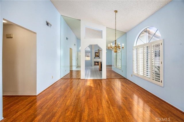 interior space with an inviting chandelier, lofted ceiling, hardwood / wood-style floors, and a textured ceiling