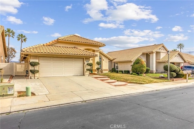 mediterranean / spanish-style home featuring an attached garage, a tile roof, driveway, a gate, and stucco siding