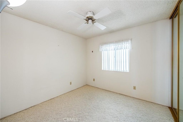 unfurnished bedroom featuring ceiling fan, light colored carpet, and a textured ceiling