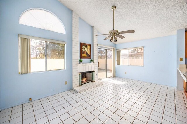 unfurnished living room with light tile patterned floors, ceiling fan, a textured ceiling, a brick fireplace, and vaulted ceiling