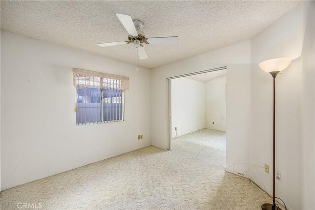 carpeted empty room featuring ceiling fan and a textured ceiling