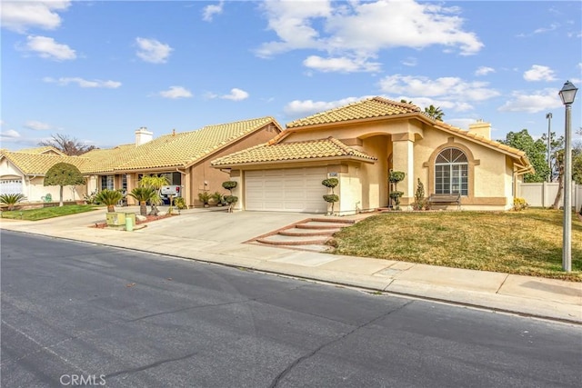 mediterranean / spanish-style house featuring concrete driveway, a tiled roof, an attached garage, and stucco siding