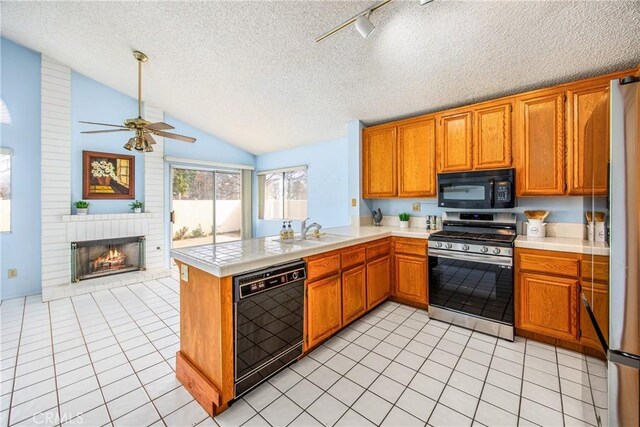 kitchen with black appliances, sink, light tile patterned floors, kitchen peninsula, and a brick fireplace