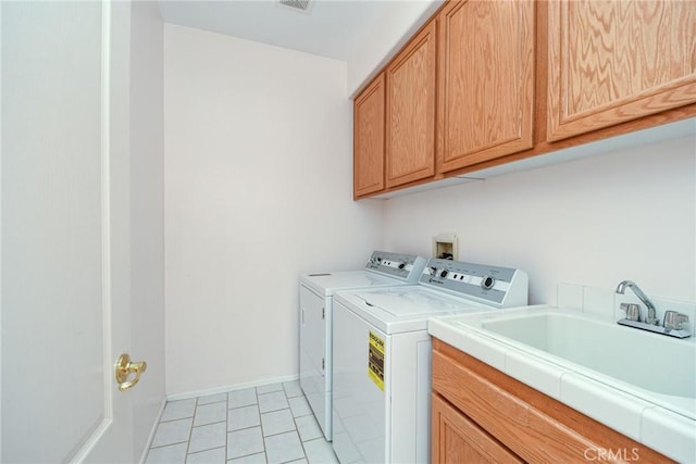 laundry area featuring sink, washing machine and dryer, cabinets, and light tile patterned flooring