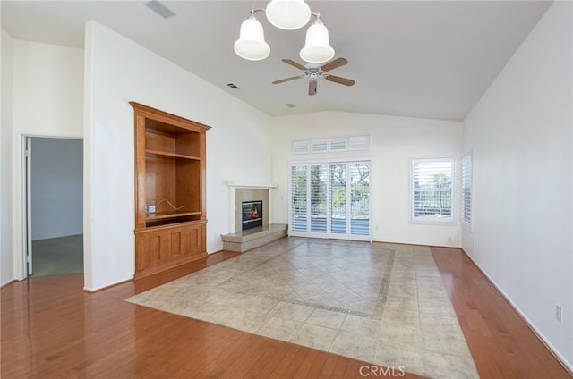 unfurnished living room featuring built in shelves, high vaulted ceiling, ceiling fan, and light wood-type flooring