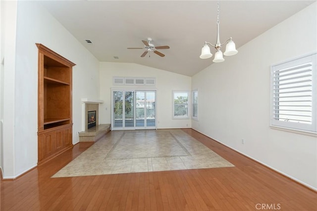 unfurnished living room with vaulted ceiling, ceiling fan with notable chandelier, and light hardwood / wood-style floors