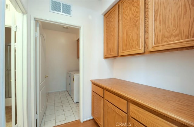 laundry area with light tile patterned flooring and washer and dryer