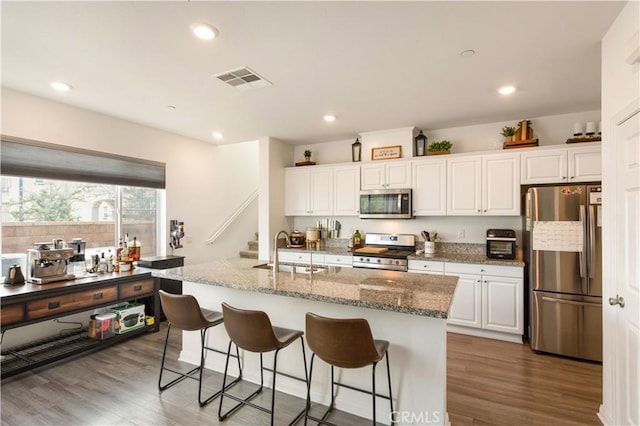 kitchen featuring white cabinetry, sink, stainless steel appliances, and a center island with sink