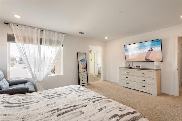 bedroom with light carpet and connected bathroom