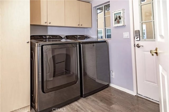 clothes washing area featuring independent washer and dryer, hardwood / wood-style floors, and cabinets