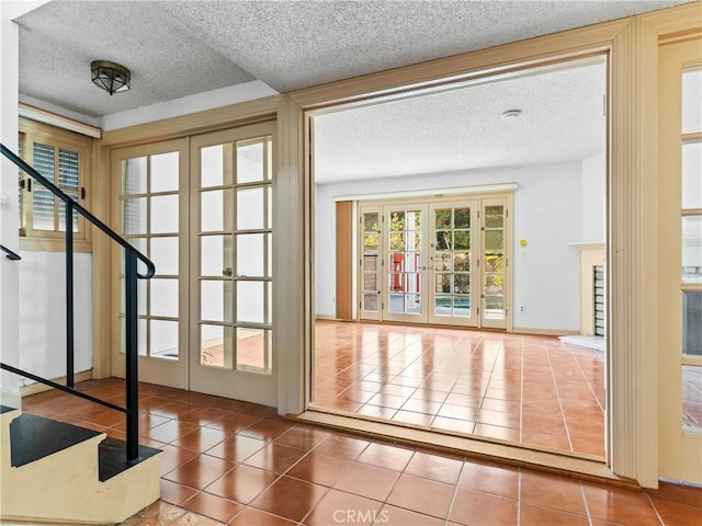 doorway featuring french doors, tile patterned floors, and a textured ceiling