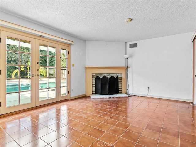 unfurnished living room featuring french doors, tile patterned floors, and a textured ceiling