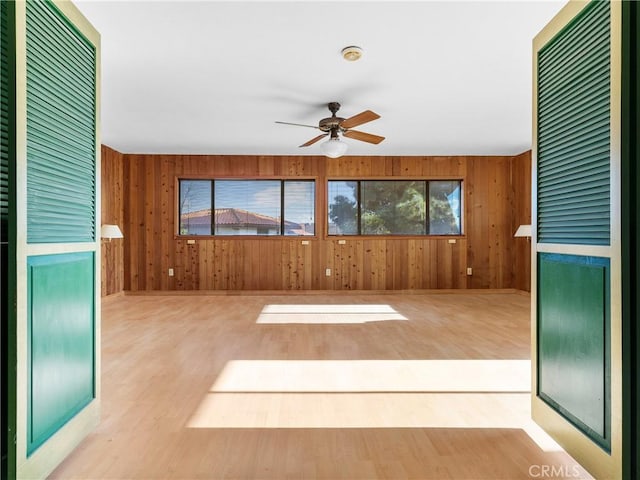 interior space featuring light hardwood / wood-style floors, ceiling fan, and wood walls