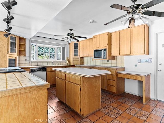 kitchen with appliances with stainless steel finishes, dark tile patterned flooring, decorative backsplash, a center island, and ceiling fan