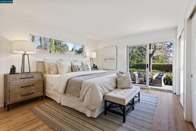 bedroom featuring wood-type flooring, multiple windows, and access to outside