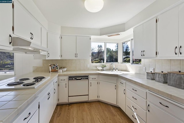 kitchen with white cabinetry, sink, white appliances, and tile counters