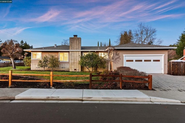 ranch-style house with a garage and a lawn