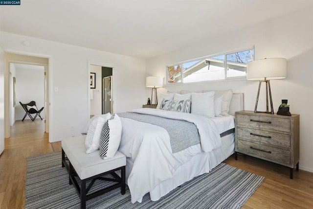 bedroom with hardwood / wood-style floors and ensuite bath